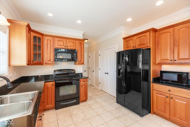 kitchen featuring dark countertops, glass insert cabinets, ornamental molding, black appliances, and a sink