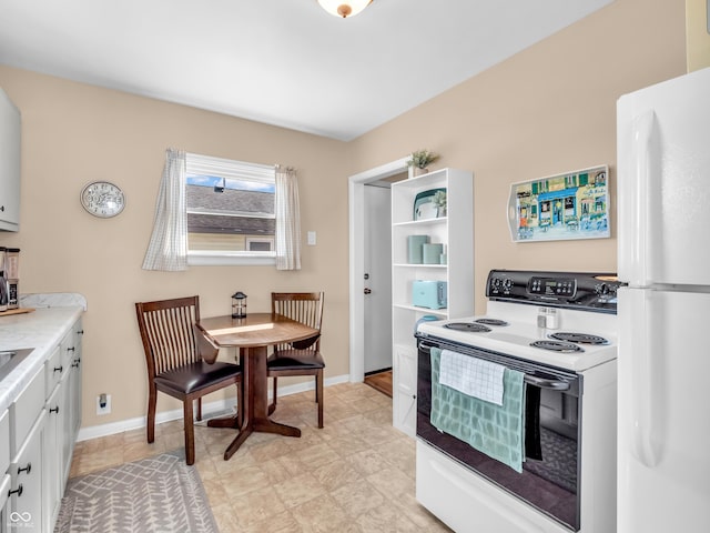 kitchen with white appliances, baseboards, white cabinetry, and light countertops