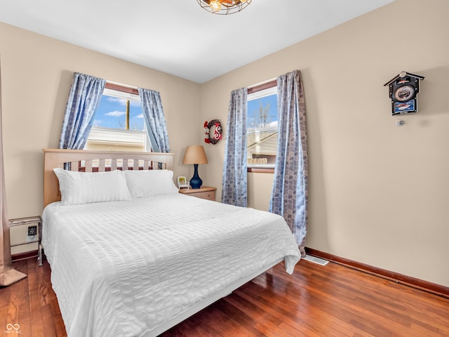 bedroom featuring hardwood / wood-style flooring, visible vents, and baseboards