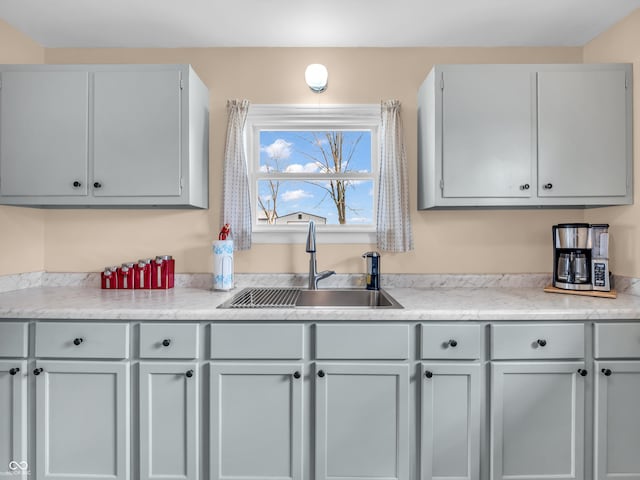 kitchen with light countertops, a sink, and gray cabinetry