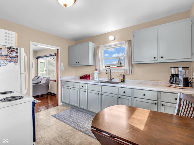 kitchen with plenty of natural light, white appliances, a sink, and gray cabinetry