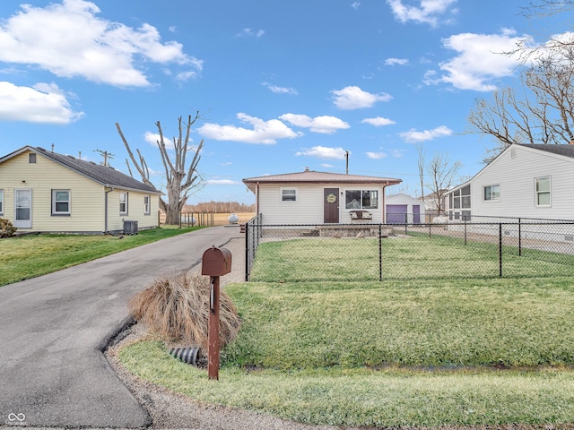 view of front of home featuring driveway, central AC unit, a front lawn, and fence