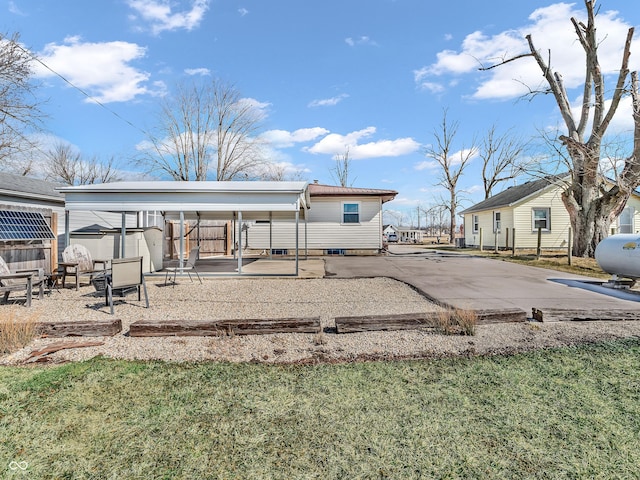 rear view of house with driveway and fence