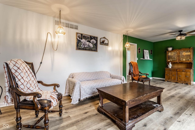 living area featuring a ceiling fan, baseboards, visible vents, and wood finished floors