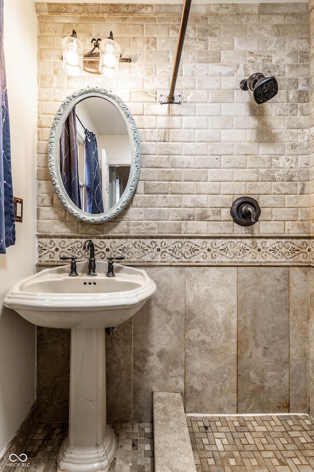 bathroom featuring tiled shower and a sink