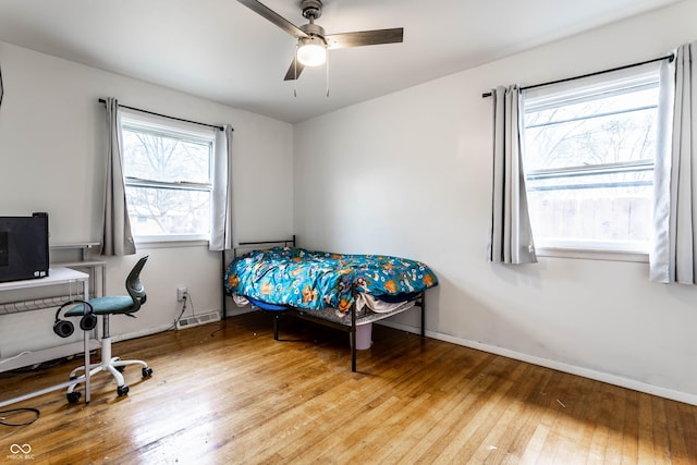 bedroom featuring hardwood / wood-style floors, a ceiling fan, visible vents, and baseboards