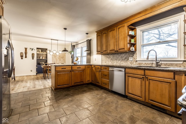 kitchen featuring decorative backsplash, brown cabinetry, a peninsula, refrigerator with ice dispenser, and stainless steel dishwasher