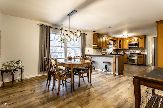 dining room with a notable chandelier, dark wood finished floors, and baseboards