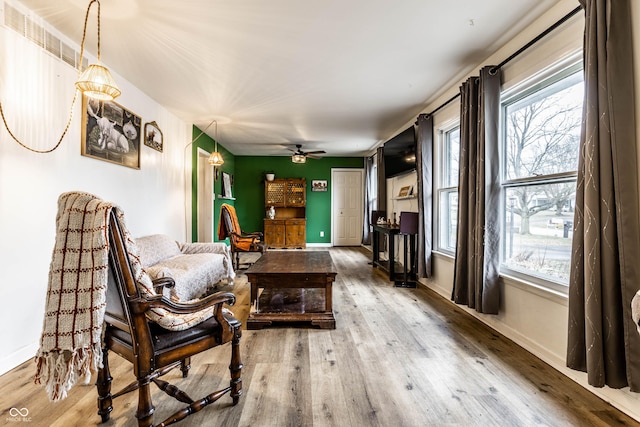 living area featuring ceiling fan, wood finished floors, and baseboards