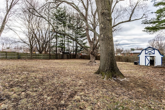 view of yard featuring an outbuilding, a fenced backyard, and a storage shed