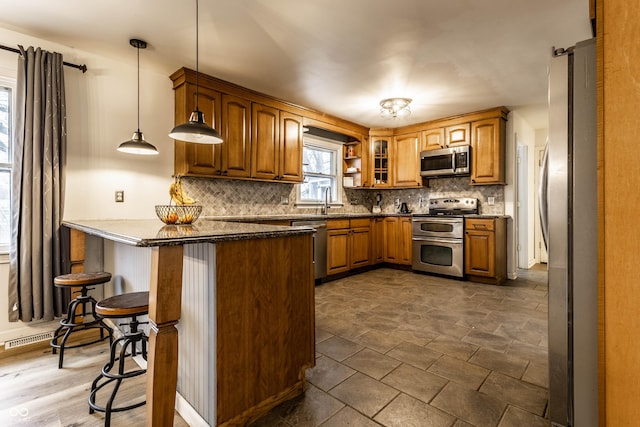 kitchen with a peninsula, tasteful backsplash, appliances with stainless steel finishes, and a kitchen breakfast bar