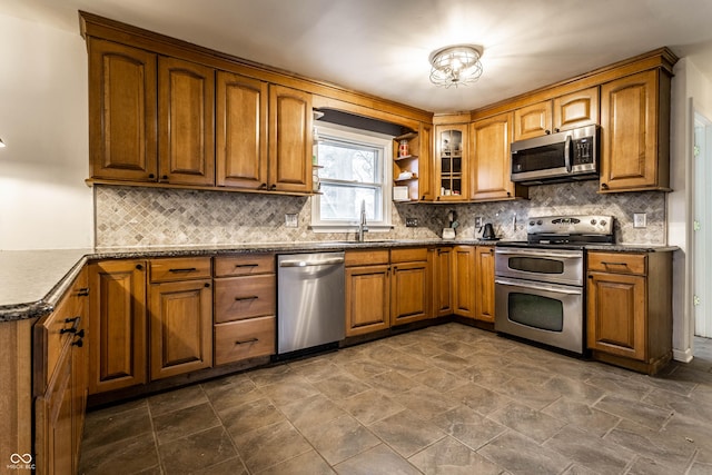 kitchen featuring appliances with stainless steel finishes, backsplash, a sink, and brown cabinets