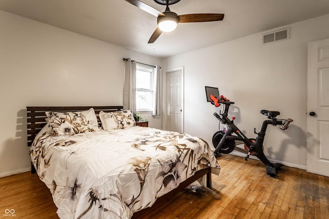 bedroom with baseboards, visible vents, ceiling fan, and hardwood / wood-style floors