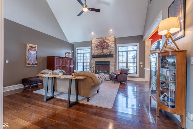 living area with dark wood finished floors, high vaulted ceiling, a fireplace, and ceiling fan