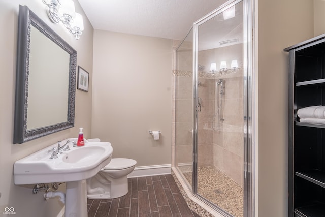 bathroom featuring a shower stall, toilet, baseboards, and wood tiled floor