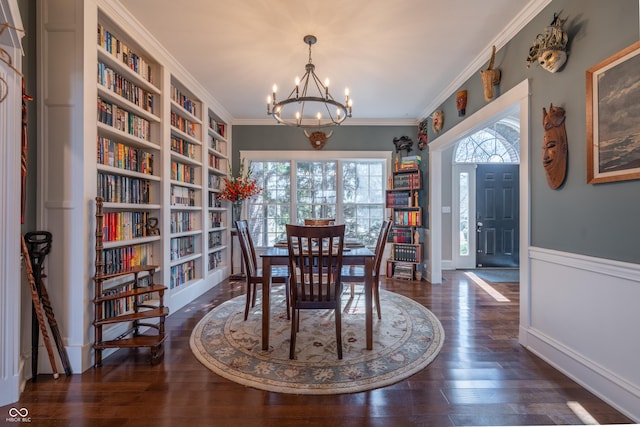 dining space with crown molding, hardwood / wood-style flooring, a healthy amount of sunlight, and a chandelier