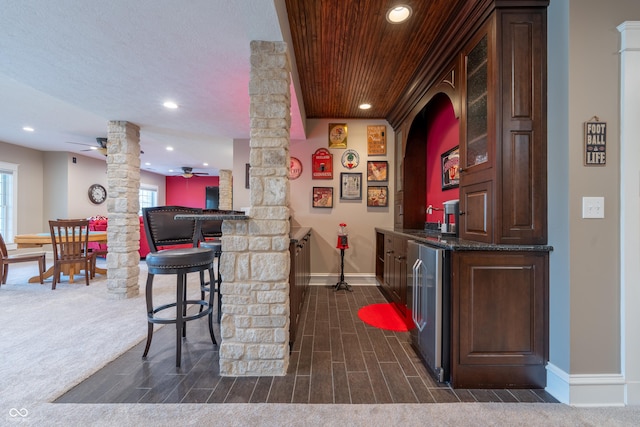 bar featuring wine cooler, wet bar, baseboards, ceiling fan, and ornate columns