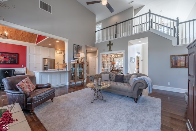 living area featuring dark wood-style floors, visible vents, baseboards, and a ceiling fan