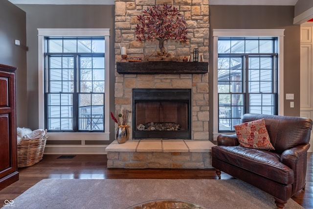 living area with a fireplace, visible vents, wood finished floors, and baseboards