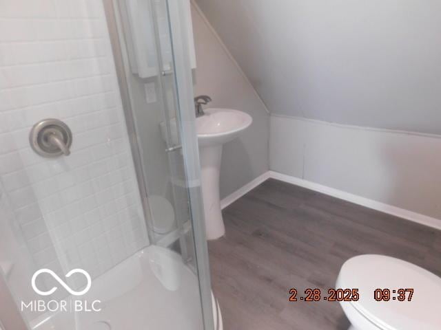 full bath featuring lofted ceiling, toilet, wood finished floors, baseboards, and a stall shower