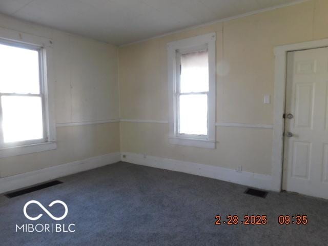 carpeted spare room with visible vents and baseboards