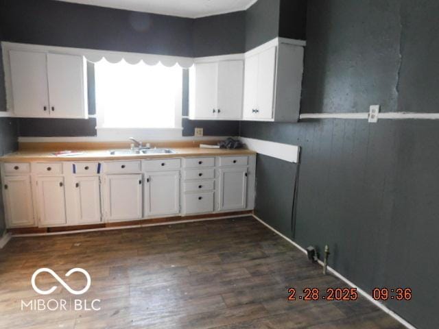 kitchen with light countertops, dark wood-style flooring, white cabinets, and a sink