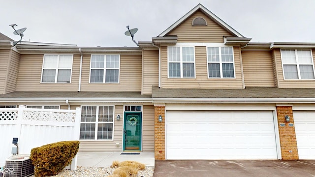 view of property with central air condition unit, driveway, fence, an attached garage, and brick siding