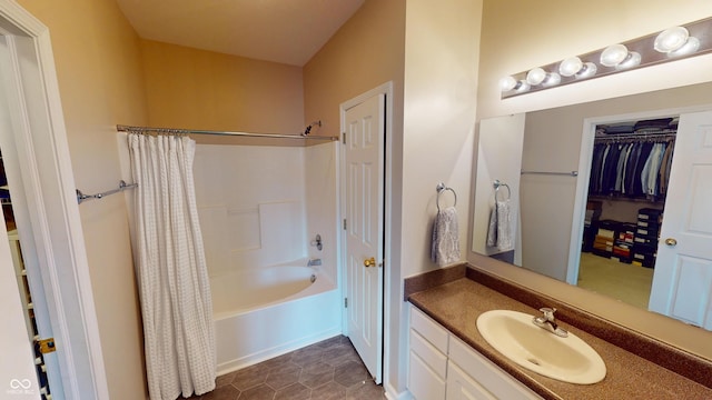 full bathroom with shower / tub combo with curtain, a spacious closet, and vanity