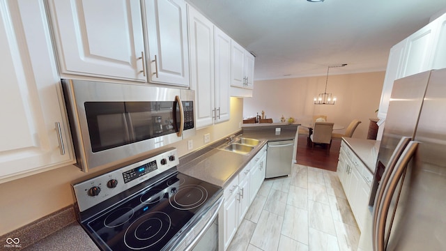 kitchen featuring a sink, stainless steel appliances, pendant lighting, white cabinetry, and a chandelier