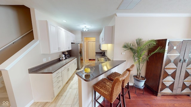 kitchen with a breakfast bar, dark countertops, light wood-style flooring, and visible vents