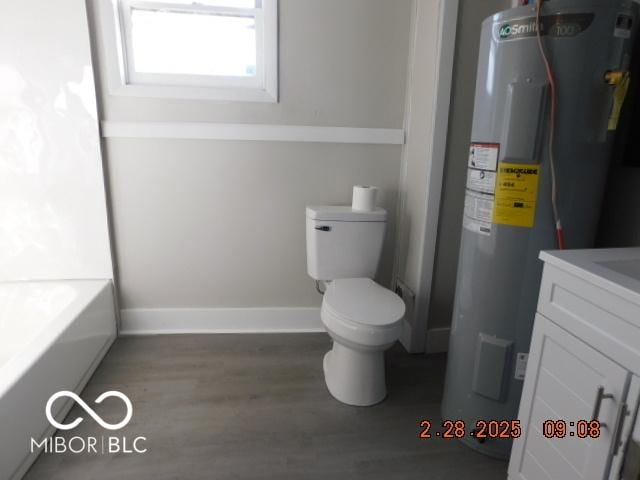 full bath featuring baseboards, toilet, wood finished floors, electric water heater, and vanity