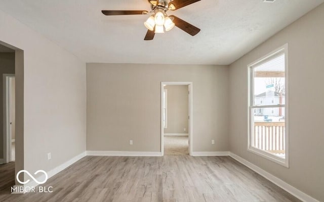 spare room with wood finished floors, a ceiling fan, and baseboards