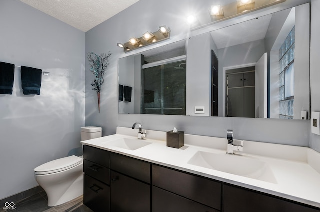 bathroom featuring a textured ceiling, toilet, a stall shower, and a sink