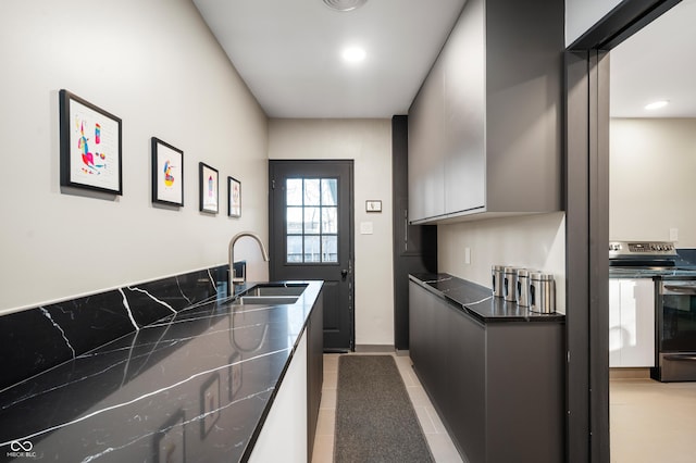 kitchen with a sink, dark countertops, stainless steel electric stove, and modern cabinets