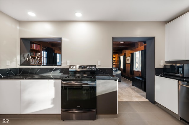 kitchen with stainless steel appliances, dark countertops, and white cabinets