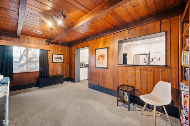 sitting room with beam ceiling, wooden walls, and wood ceiling