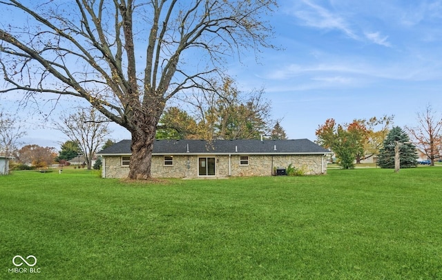 rear view of house with stone siding and a lawn