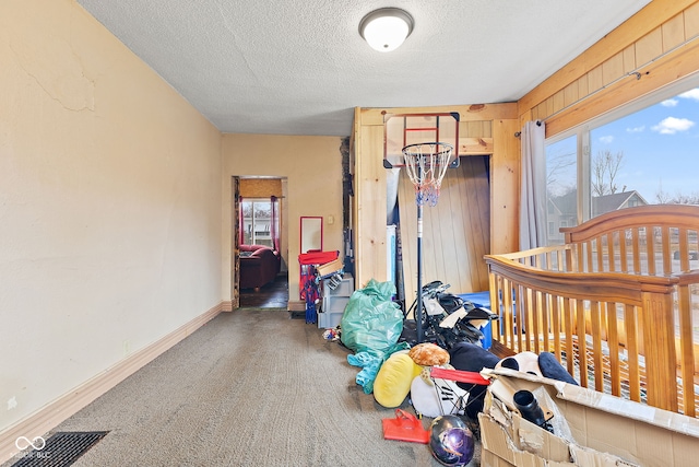 carpeted bedroom featuring visible vents, wooden walls, baseboards, and a textured ceiling