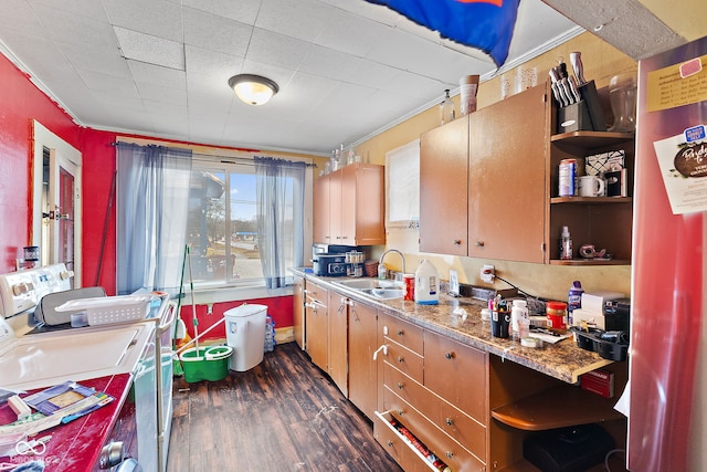 kitchen featuring dark wood finished floors, open shelves, ornamental molding, a sink, and washer and dryer