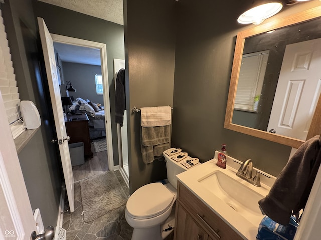 full bathroom featuring ensuite bathroom, a textured ceiling, toilet, vanity, and a shower stall