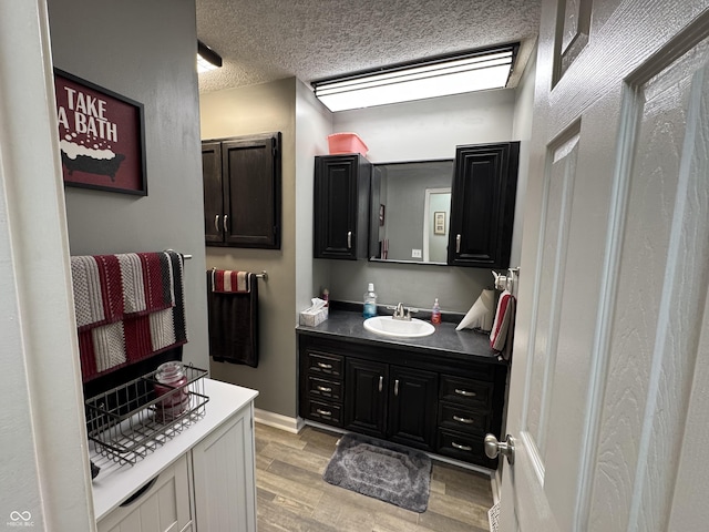 bathroom with a textured ceiling, wood finished floors, and vanity