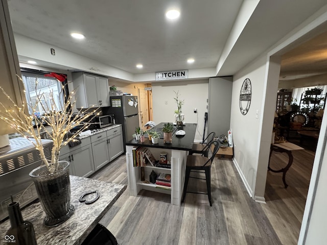 kitchen featuring recessed lighting, gray cabinetry, wood finished floors, baseboards, and appliances with stainless steel finishes