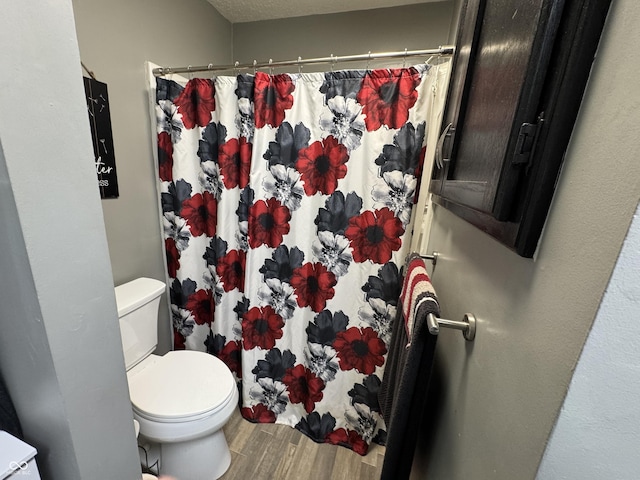 full bath featuring toilet, curtained shower, and wood finished floors