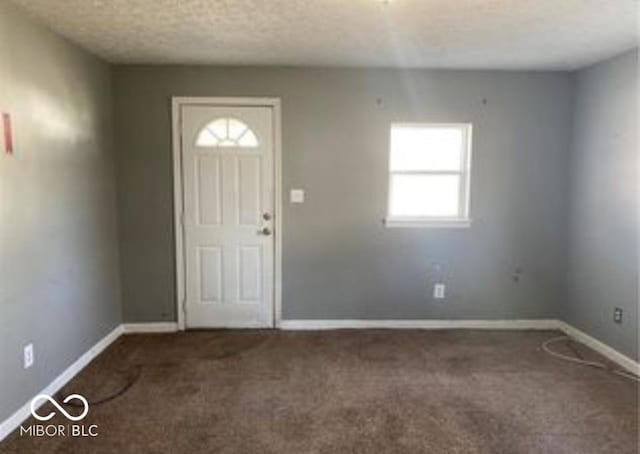 carpeted entrance foyer with a textured ceiling and baseboards