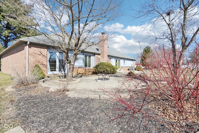 exterior space with a patio, brick siding, and a chimney