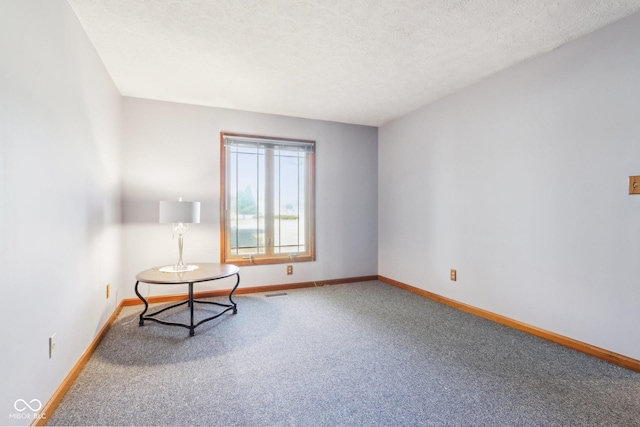 unfurnished room with visible vents, baseboards, carpet floors, and a textured ceiling