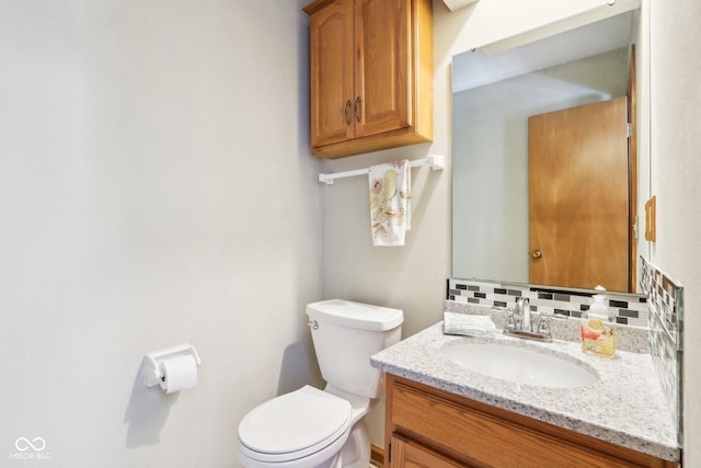 half bath with backsplash, toilet, and vanity