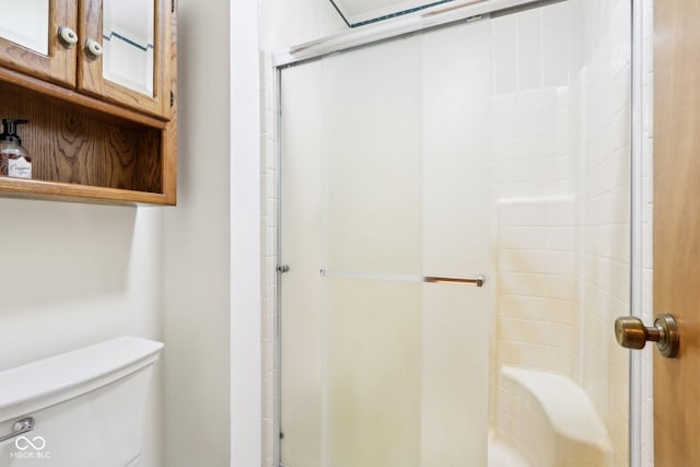 bathroom featuring a shower with shower door and toilet