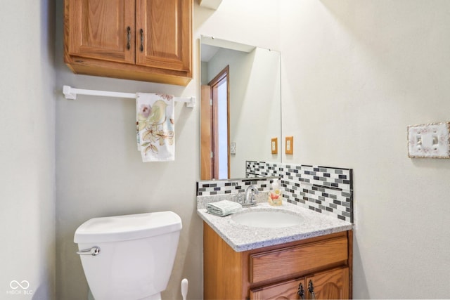 half bathroom featuring decorative backsplash, toilet, and vanity