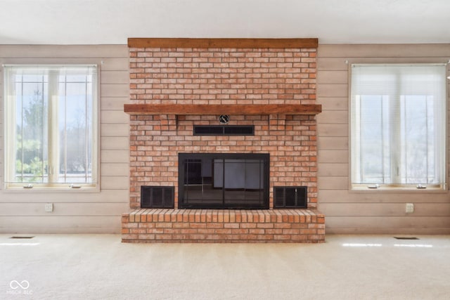 unfurnished living room featuring a brick fireplace, wood walls, and carpet floors